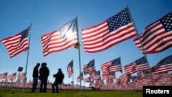 Veteran perang Vietnam Jake Thorn (kanan) berbincang dengan Vicki Martinez (tengah) dan Scott Mulligan (kiri) tentang pengalamannya selama beragabung dalam militer AS diantara 2.013 bendera AS yang dipajang untuk menghormati jasa para pahlawan dalam perayaan Hari Veteran di Aurora Healing Fields, Illinois (10/11).