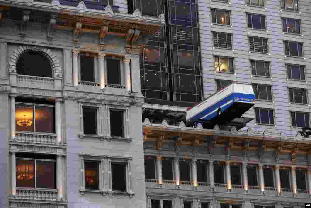 An art installation entitled &quot;Hang On A Minute Lads, I&#39;ve Got A Great Idea&quot; created by British artist Richard Wilson and depicting a full-sized bus, is displayed outside the building of The Peninsula hotel in Hong Kong.