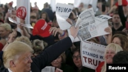 U.S. Republican presidential candidate Donald Trump holds up a newspaper with a headline reading "Clinton, Trump Lead" at a campaign rally in Warwick, Rhode Island, April 25, 2016. 