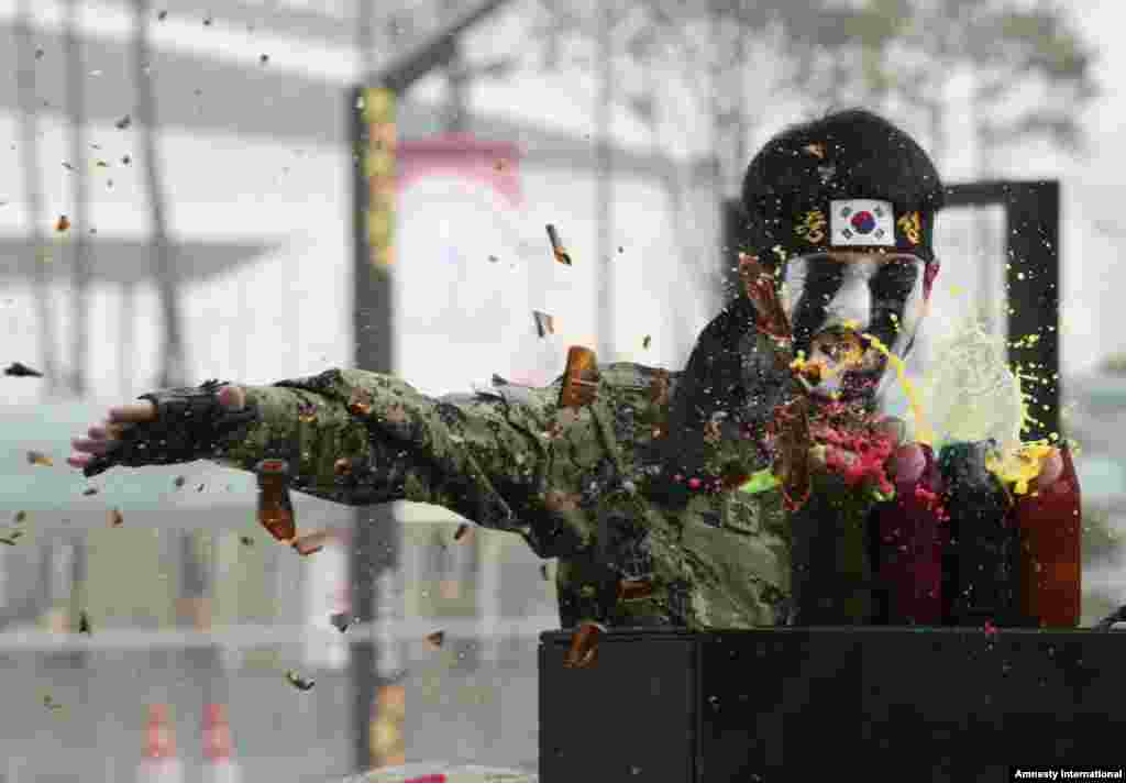 A member of the South Korean Army Special Forces uses his hand to break beer bottles containing colored liquids during the Seoul International Aerospace and Defense Exhibition 2013 in Goyang, South Korea.