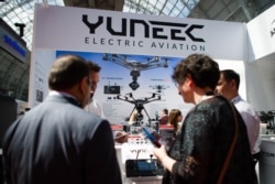 FILE - Visitors look at the products on the Yuneec electric aviation stand, during the Security and Counter Terror Expo at the Olympia center in west London, April 19, 2016.