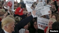 U.S. Republican presidential candidate Donald Trump holds up a newspaper with a headline reading "Clinton, Trump Lead" at a campaign rally in Warwick, Rhode Island, April 25, 2016. 