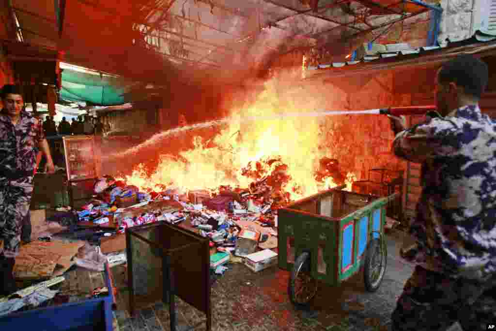 Members of the Palestinian Civil Defense hose down a shop that caught on fire due to clashes between Palestinians and Israeli soldiers in the West Bank city of Jenin, June 19, 2014.