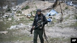 A Libyan rebel fighter carries a heavy machine gun in the besieged city of Misrata, Libya, April 23, 2011