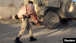 Un homme assurant la sécurité porte un homme blessé après une attaque à Lashkar Gah, dans la province de Helmand, Afghanistan, le 15 novembre 2015.