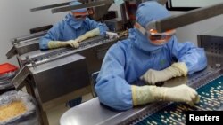 Employees inspect tablets as they move along the production line at a pharmaceutical plant of Lupin, India's No. 2 drugmaker, in Verna, in the western state of Goa, India, June 9, 2017. 