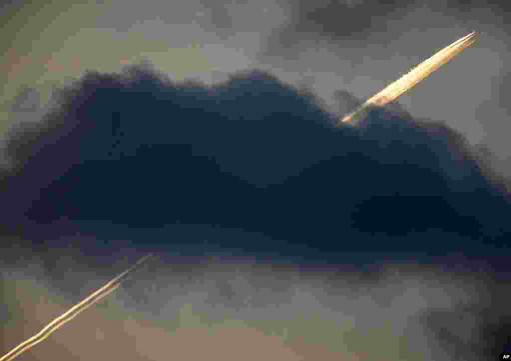 An aircraft flies over Frankfurt, leaving contrails above the cloud.