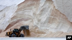 A front-end loader works in front of a pile of road salt, Jan. 28, 2022, in Chelsea, Mass. 