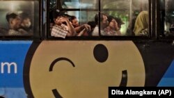 Penumpang menaiki bus dalam kota yang dihiasi dengan iklan dari sebuah situs toko online di Jakarta pada 7 Maret 2014. (Foto: AP/Dita Alangkara)