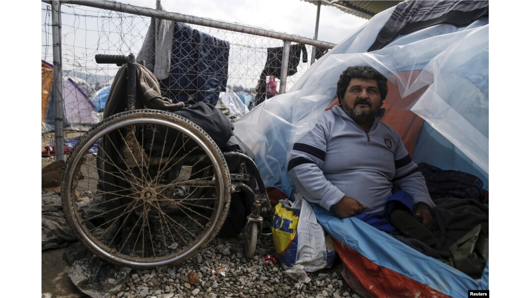 Iraqi refugee Hassan Omar, 48, poses inside his tent next to his wheelchair at a makeshift camp for refugees and migrants at the Greek-Macedonian border near Idomeni, Greece, March 17, 2016.