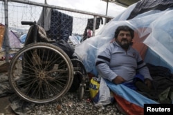Iraqi refugee Hassan Omar, 48, poses inside his tent next to his wheelchair at a makeshift camp for refugees and migrants at the Greek-Macedonian border near Idomeni, Greece, March 17, 2016.