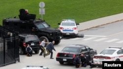 Police officers take cover near Parliament Hill following a shooting incident in Ottawa, October 22, 2014.