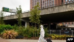FILE - A student wearing full-body PPE due to the COVID-19 pandemic walks toward the Coventry University Library at the beginning of the new academic year, at Coventry University, in Coventry, central England, Sept. 23, 2020.