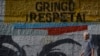 ARCHIVO - Un hombre pasa frente a un mural con la frase en español: "¡Gringo, respeta!", en Caracas, Venezuela, el miércoles 5 de febrero de 2020. 