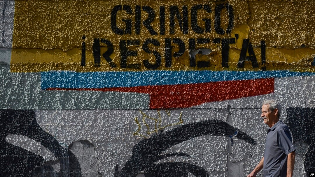 ARCHIVO - Un hombre pasa frente a un mural con la frase en español: "¡Gringo, respeta!", en Caracas, Venezuela, el miércoles 5 de febrero de 2020. 