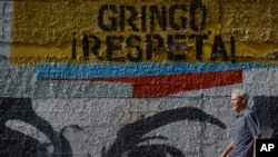 ARCHIVO - Un hombre pasa frente a un mural con la frase en español: "¡Gringo, respeta!", en Caracas, Venezuela, el miércoles 5 de febrero de 2020. 