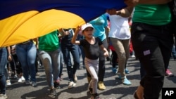 Una niña avanza mientras ayuda a sostener una bandera en una marcha progubernamental en el Día Internacional de la Mujer en Caracas, el 8 de marzo de 2020.