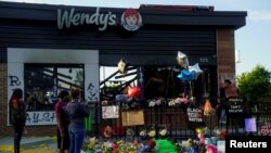 FILE - People take photos of a memorial to Rayshard Brooks at the Wendy's where he was shot and killed by police officers, in Atlanta, Georgia, June 17, 2020.
