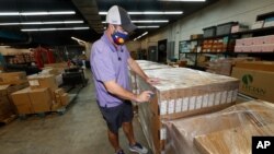 Jason Rand cuts open the shrink wrap around a pallet of Lenovo Chromebook laptops as they sit in a Denver Public Schools warehouse after arriving Friday, Aug. 21, 2020, in Denver. Schools across the United States are facing shortages and long delays…