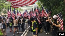 Para pengunjuk rasa berpawai sambil mengibarkan bendera AS di Hong Kong. (Foto: Iris Tong/VOA)