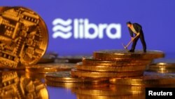 Una pequeña figura de juguete se encuentra en representaciones de moneda virtual frente al logotipo de Libra en esta ilustración.