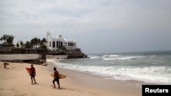 FILE - Surfers walk along a beach in Mazatlan, state of Sinaloa, Mexico.