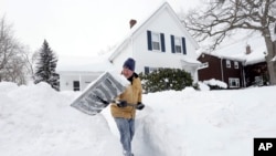 A storm brought a new round of wind-whipped snow to New England on Sunday. Tom Mulkern shovels snow in front of his home in Norwood, Mass., Feb. 15, 2015.