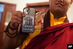 Jalue Dorje shows his Drake London, Atlanta Falcons, rookie card, which sits in the back of his phone, at his 18th birthday and enthronement ceremony at the Tibetan American Foundation of Minnesota, Nov. 9, 2024, in Isanti.