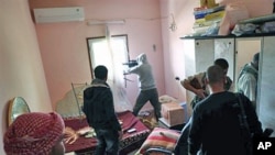 Libyan rebel fighters are seen in the room of a house while a comrade fires from a window at pro-Gadhafi troops in the besieged city of Misrata, the main rebel holdout in Gadhafi's territory, April 22, 2011