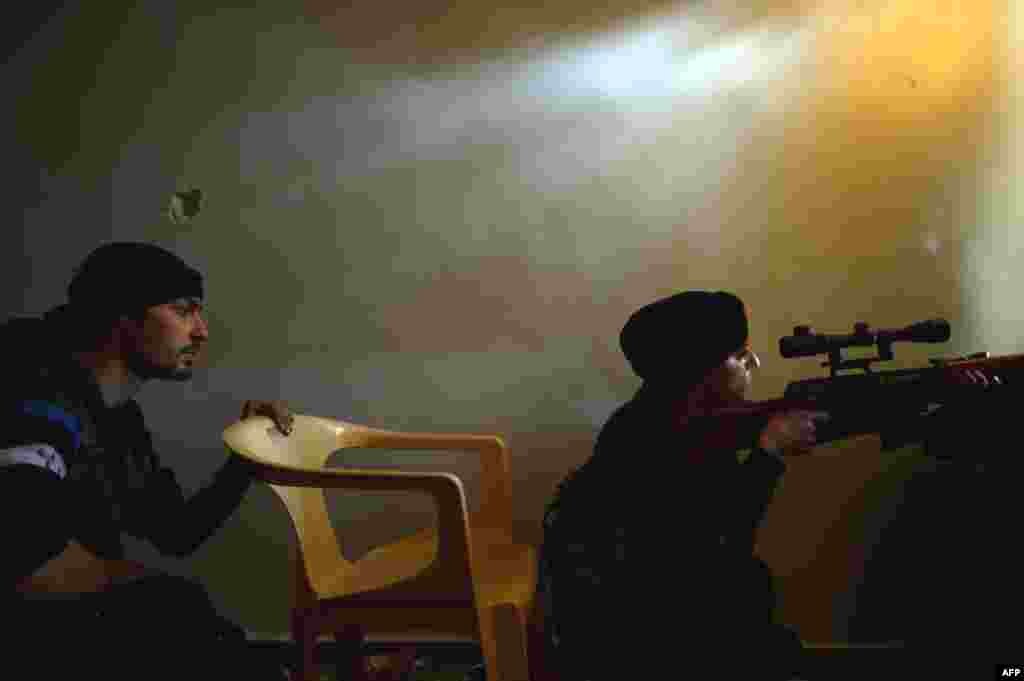 A Syrian rebel monitors the movement of Syrian government forces in the Sheikh Maqsud district of the northern Syrian city of Aleppo, on April 11, 2013.