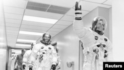 FILE - Apollo 11 astronaut Neil Armstrong waves to well-wishers on the way out to the transfer van, Cape Canaveral, Florida, July 16, 1969. Mike Collins and Buzz Aldrin follow Armstrong down the hallway.