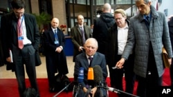 German Finance Minister Wolfgang Schaeuble, center, speaks with the media as he arrives for a meeting of eurogroup finance ministers at the EU Council building in Brussels, Nov. 14, 2013.