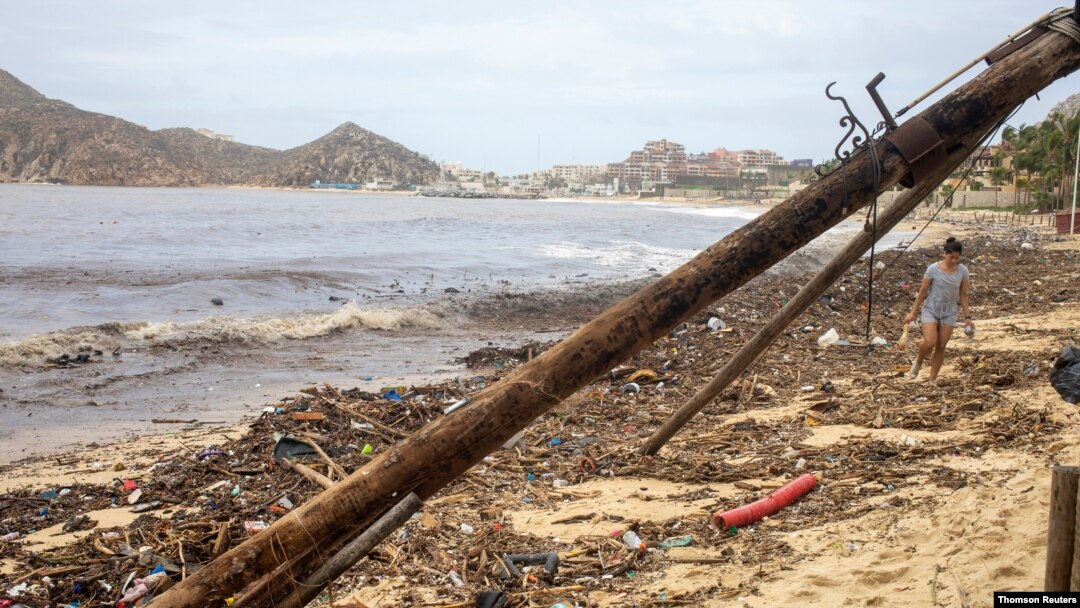 A woman walks through rubble and near a fallen lamppost on the beach after the crossing of Hurricane Genevieve in Cabo San Lucas, Mexico's Southern Baja Peninsula, Aug. 20, 2020.