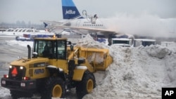 Plows clear sleet and snow from a gate at La Guardia airport, Feb. 3, 2014, in New York.