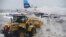 Plows clear sleet and snow from a gate at La Guardia airport, Feb. 3, 2014, in New York.