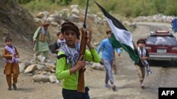 Children of local Afghan residents carrying hunting rifles and a flag walk through a road in Bandejoy area of Dara district in Panjshir province on August 21, 2021, days after the Taliban stunning takeover of Afghanistan. (Photo by Ahmad SAHEL ARMAN…