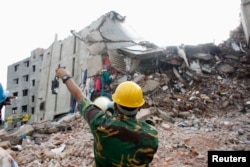 FILE - A rescue worker attempts to find survivors in the rubble of the collapsed Rana Plaza building near Dhaka, April 30, 2013.