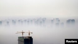 A building under construction is seen amidst smog on a polluted day in Shenyang, Liaoning province, Nov. 21, 2014.
