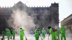 MEXICO – Municipal employees work amid a cloud of dust at Zocalo square, in Mexico City on July 20, 2020.