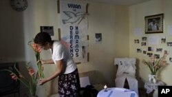 Ramona Rivero, of the Cuban dissident group Ladies in White, places flowers in a vase near a condolence book for the late dissident Wilman Villar in Havana, Cuba, Friday, Jan. 20, 2012.