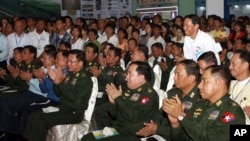 Senior General Min Aung Hlaing of Myanmar Armed Forces, centre front row, enjoys a performance as he visits a trade exhibition organized by the Union of Myanmar Economic Holding Limited (UMEHL) known as U Paing at Tatmataw Exhibition hall Friday, Dec. 20, 2013, in Yangon, Myanmar