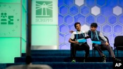 Jairam Hathwar, 13, of Painted Post, N.Y., left, and Nihar Janga, 11, of Austin, Texas, right, pat each other on the back as they hear that they will likely be announced co-champions after a drawn-out battle that did indeed end in them being named co-champions in the 2016 National Spelling Bee, in National Harbor, Md., May 26, 2016.