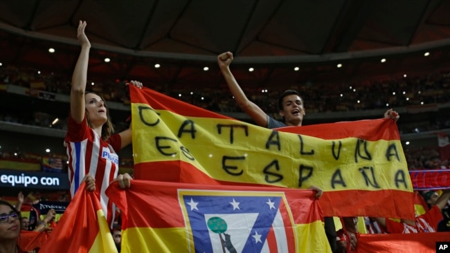Partidarios del Atlético de Madrid, sostienen una bandera española que dice: "Cataluña es España" durante un partido de fútbol de la Liga española entre el Atlético de Madrid y Barcelona en el estadio Metropolitano de Madrid, España, el 14 de octubre de 2017.