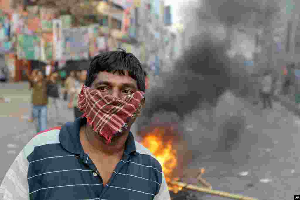 A Bangladeshi opposition activist looks on after a street vendor&#39;s cart is burned during a protest and clash with police in Dhaka. The protest was called by an alliance of 18 parties to denounce trials of several opposition politicians accused of mass killings and atrocities during Bangladesh&#39;s 1971 independence war against Pakistan. 