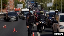 A police officer wearing a protective mask stands at a traffic checkpoint during a partial lockdown amid the coronavirus pandemic, in Madrid, Spain Oct. 9, 2020.