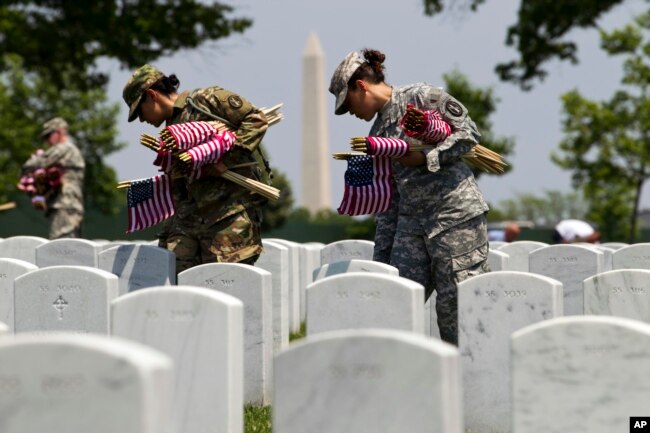 FILE - Members of the Old Guard, with the Washington Memorial in the back, place flags in front of every headstone at Arlington National Cemetery in Arlington, Va., Thursday, May 26, 2016. Soldiers were to place nearly a quarter of a million U.S. flags at the cemetery as part of a Memorial Day tradition. ( AP Photo/Jose Luis Magana)