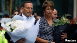 Australian Prime Minister Tony Abbott and his wife Margie prepare to place floral tributes near the cafe in central Sydney, December 16, 2014, where hostages were held for over 16-hours. 