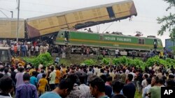 Warga menyaksikan tim SAR bekerja setelah kecelakaan antara kereta kargo dan Kanchanjunga Express, kereta penumpang, di dekat stasiun New Jalpaiguri, Bengal Barat, India, pada Senin, 17 Juni 2024. (Foto: AP)