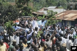 Leader of the opposition party Forum for Democratic Change Kizza Besigye, background center right, beside his wife Winnie Byayima, left, waves to large crowds of supporters as he returns from Nairobi after medical treatment, May 12, 2011