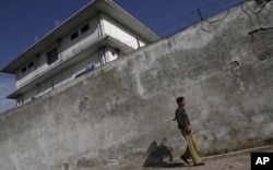 FILE- A policeman walks near the compound where Osama bin Laden was killed in Abbottabad, Pakistan, May 3, 2011. Pakistani doctor Shakil Afridi helped the U.S. locate bin Laden through a DNA sample he provided following a fake immunization campaign.
